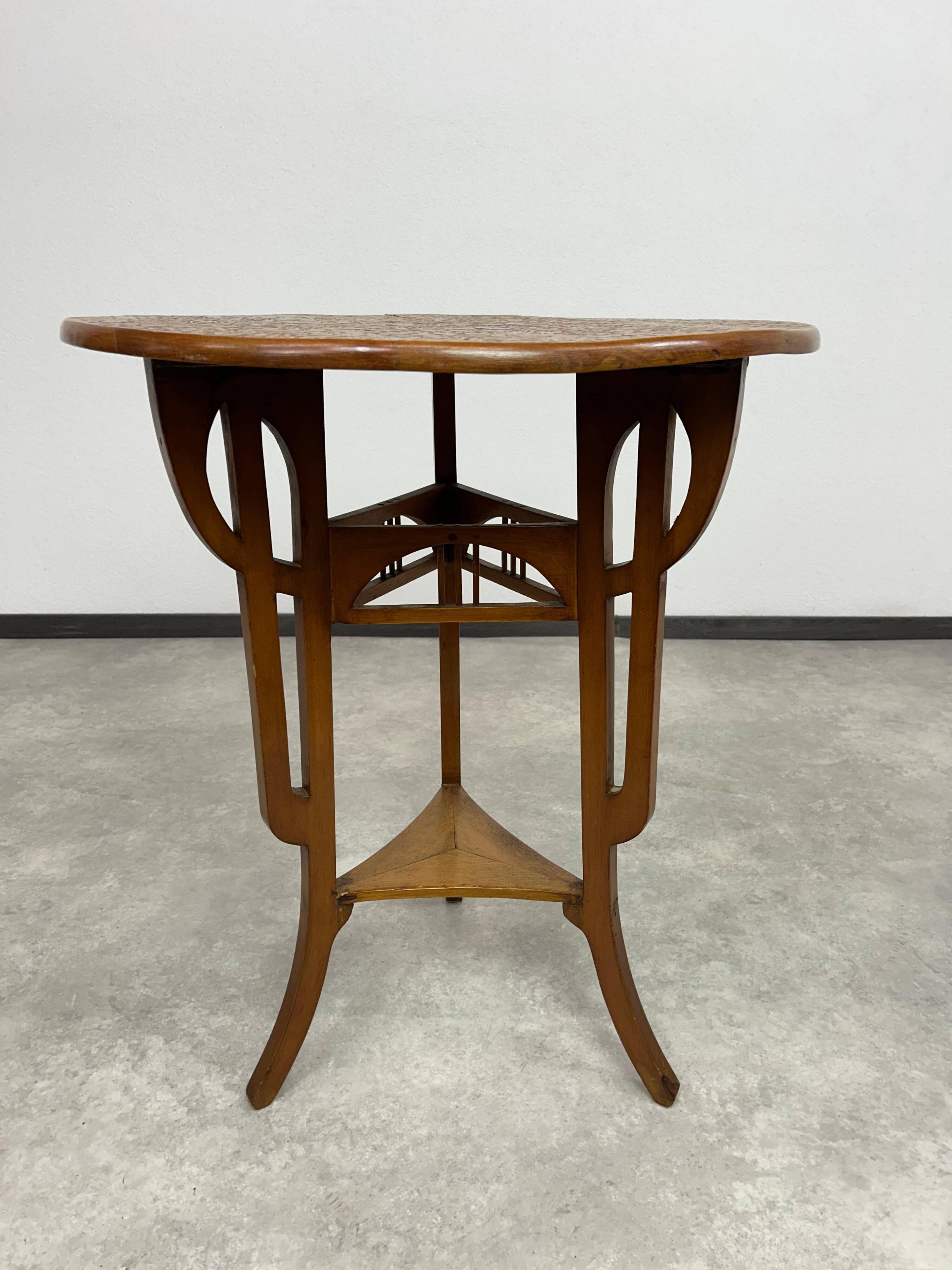 Round Art Nouveau coffee table with a sculpted top.