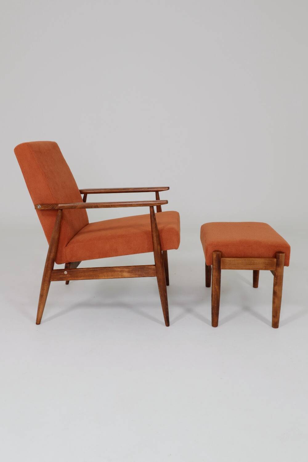Vintage armchair and footrest in orange corduroy.