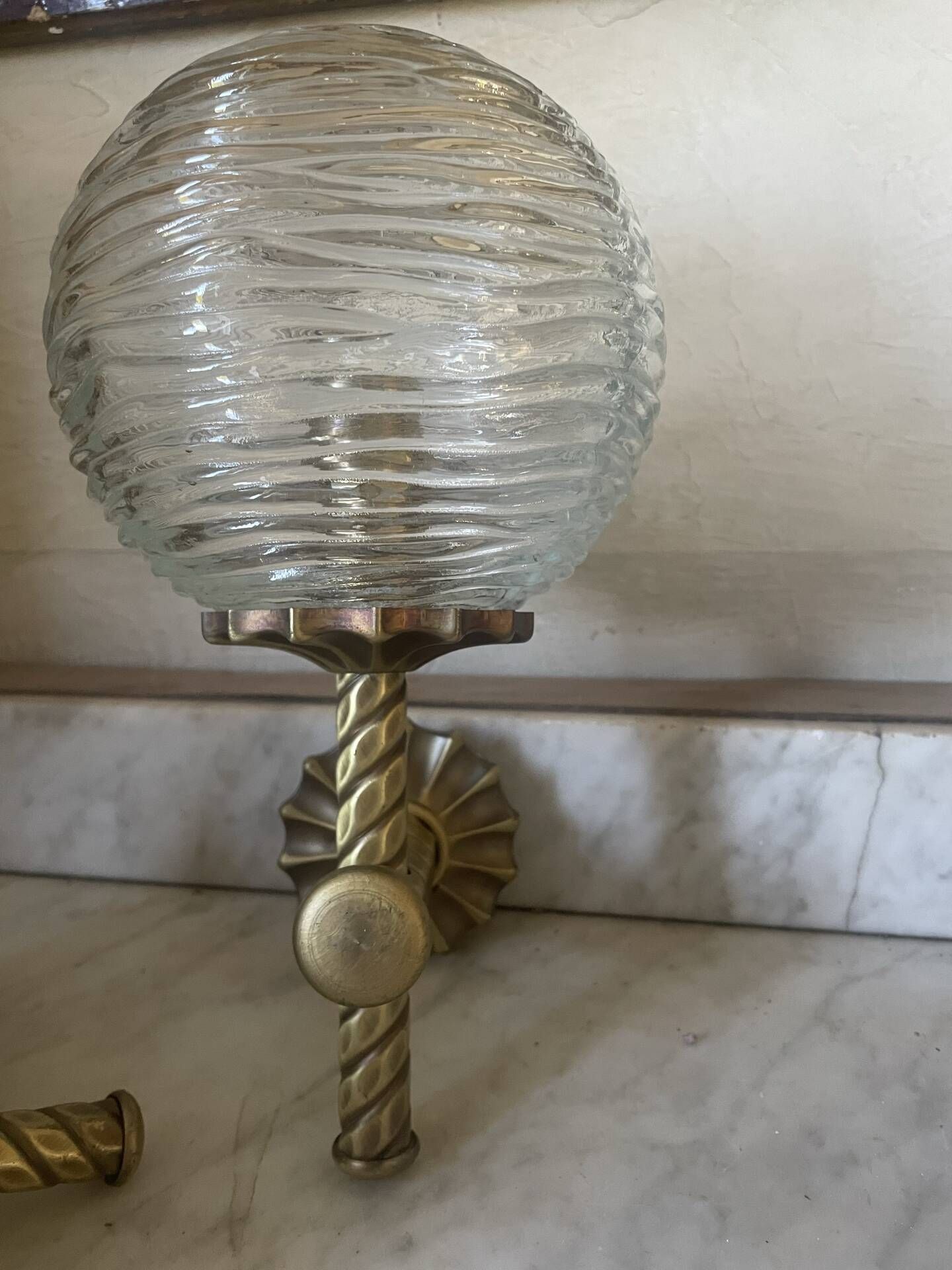 Pair of neoclassical wall sconces in twisted brass and ribbed glass.