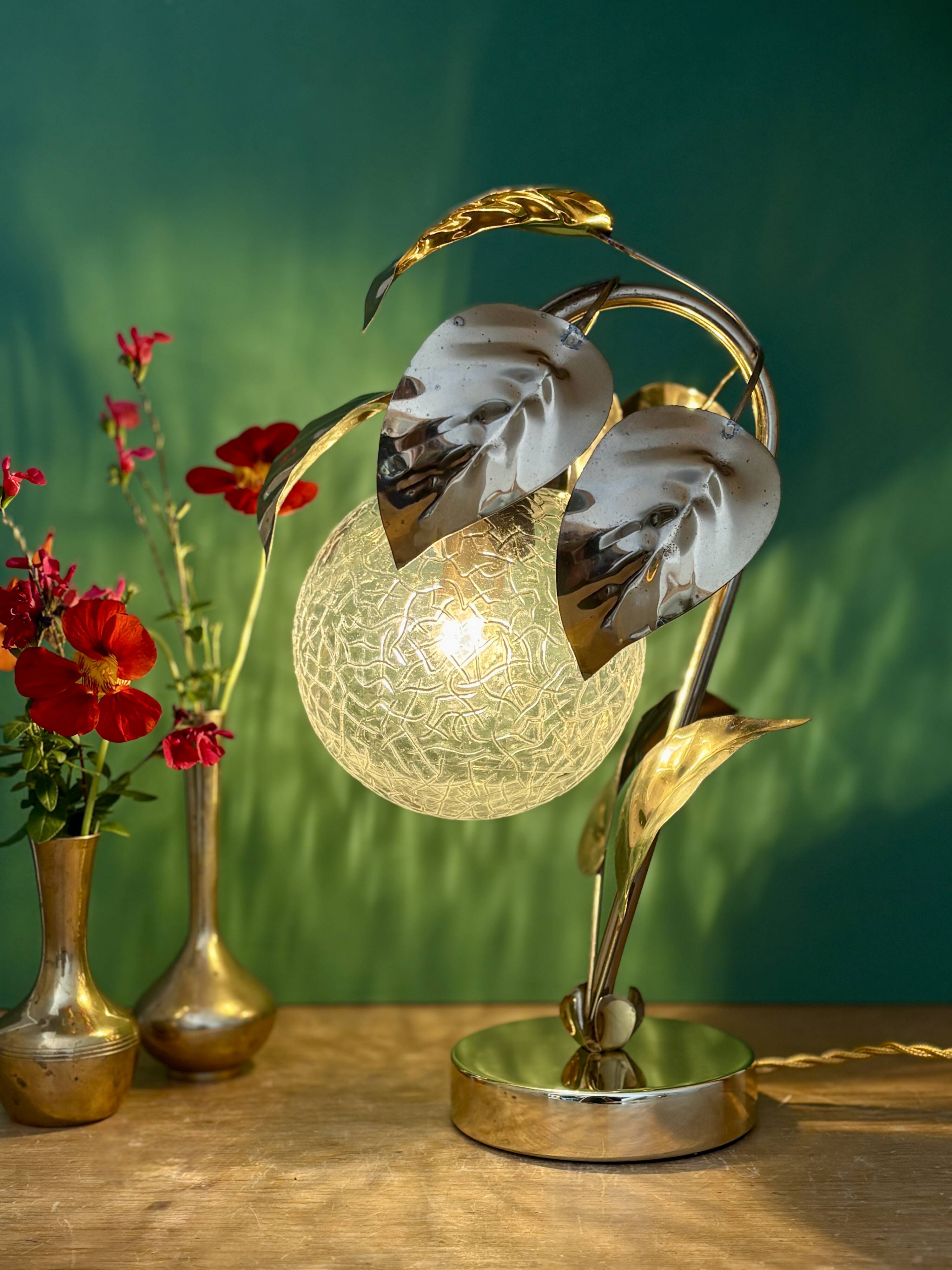 Vintage lamp with brass leaf design and transparent glass globe.