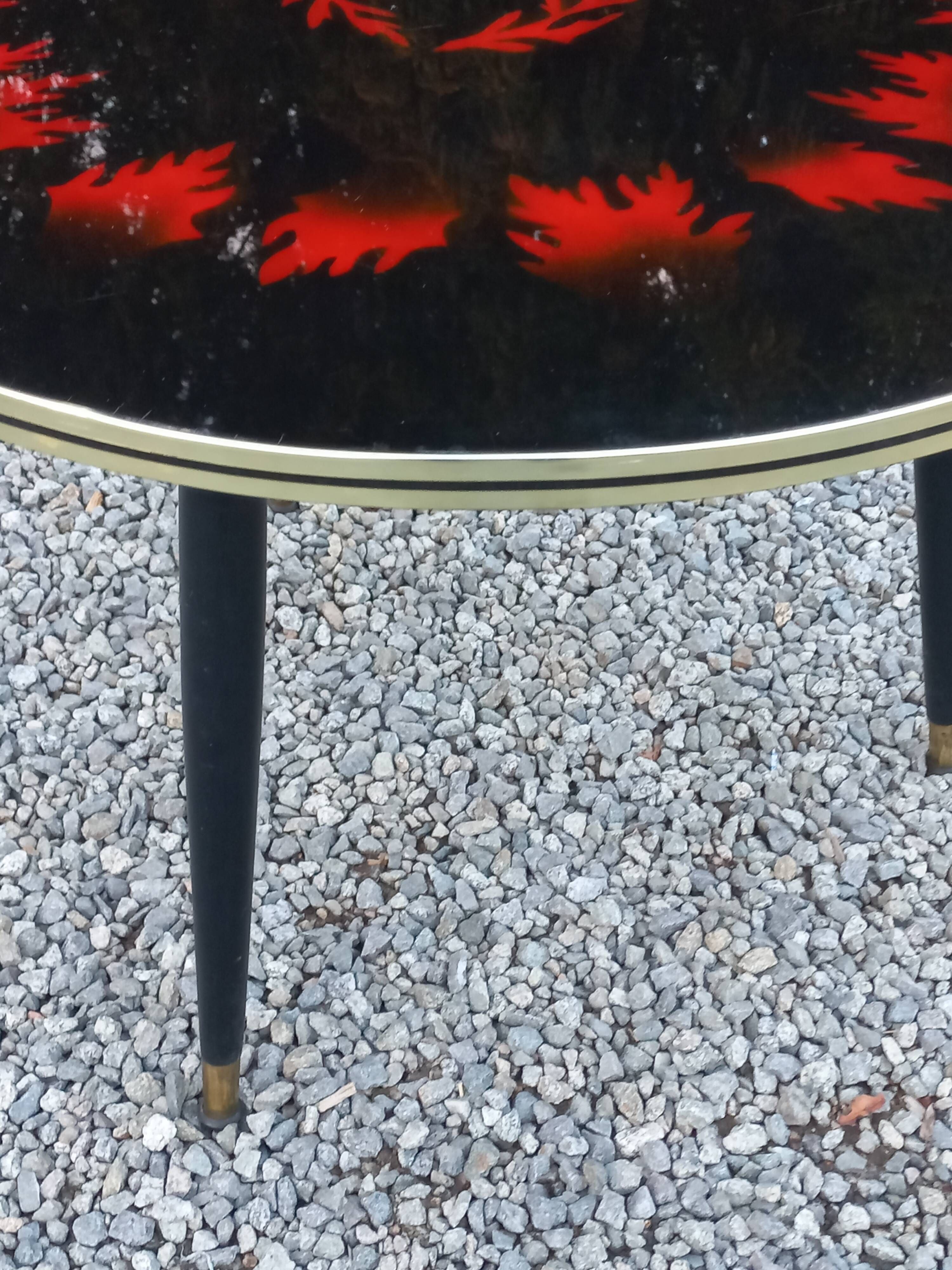 Vintage coffee table with glass top and tripod legs in blackened wood from the 1960s.