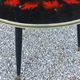 Vintage coffee table with glass top and tripod legs in blackened wood from the 1960s.