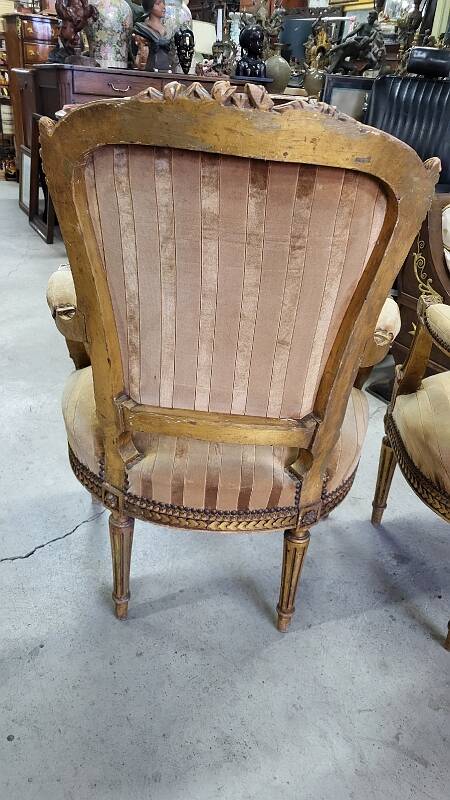 A pair of gilded wooden armchairs in the Louis XVI style.
