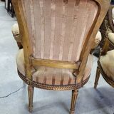 A pair of gilded wooden armchairs in the Louis XVI style.