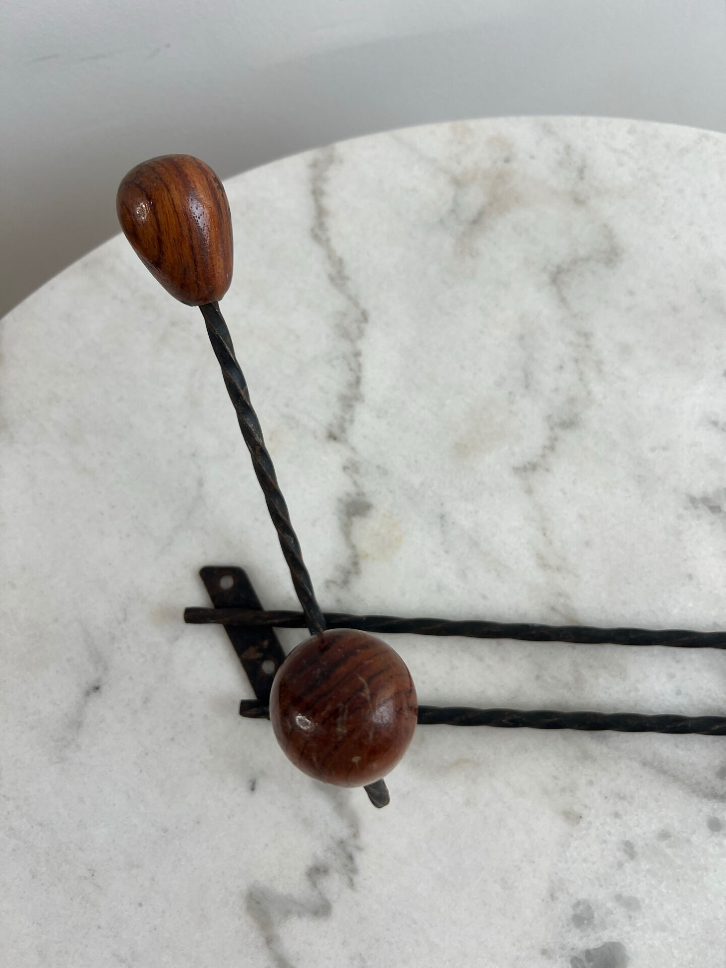 Wall-mounted coat rack in wrought iron with turned wooden knobs.