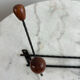 Wall-mounted coat rack in wrought iron with turned wooden knobs.
