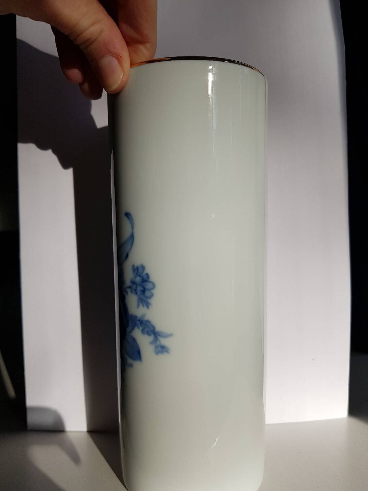 White porcelain vase from Limoges with blue decoration and gold rim.