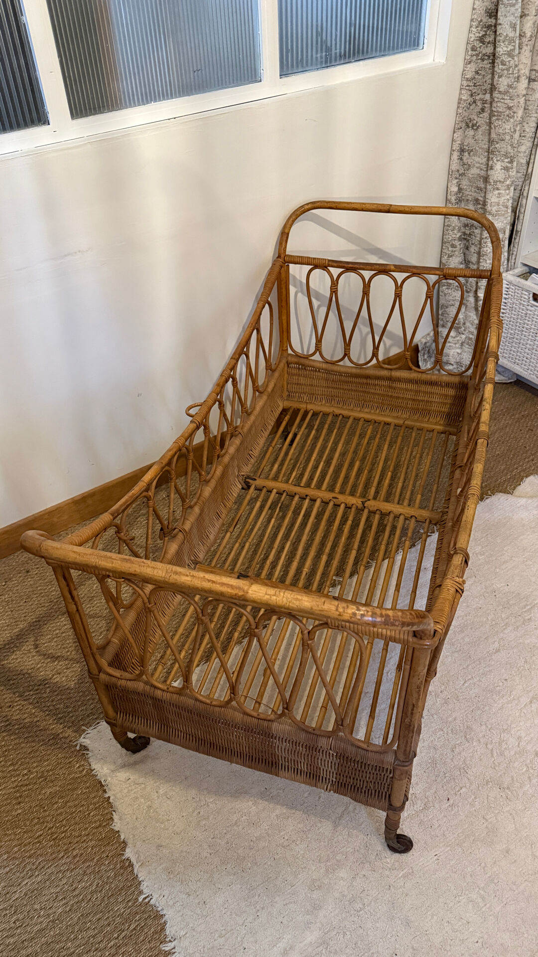 Vintage rattan baby cot on wheels.