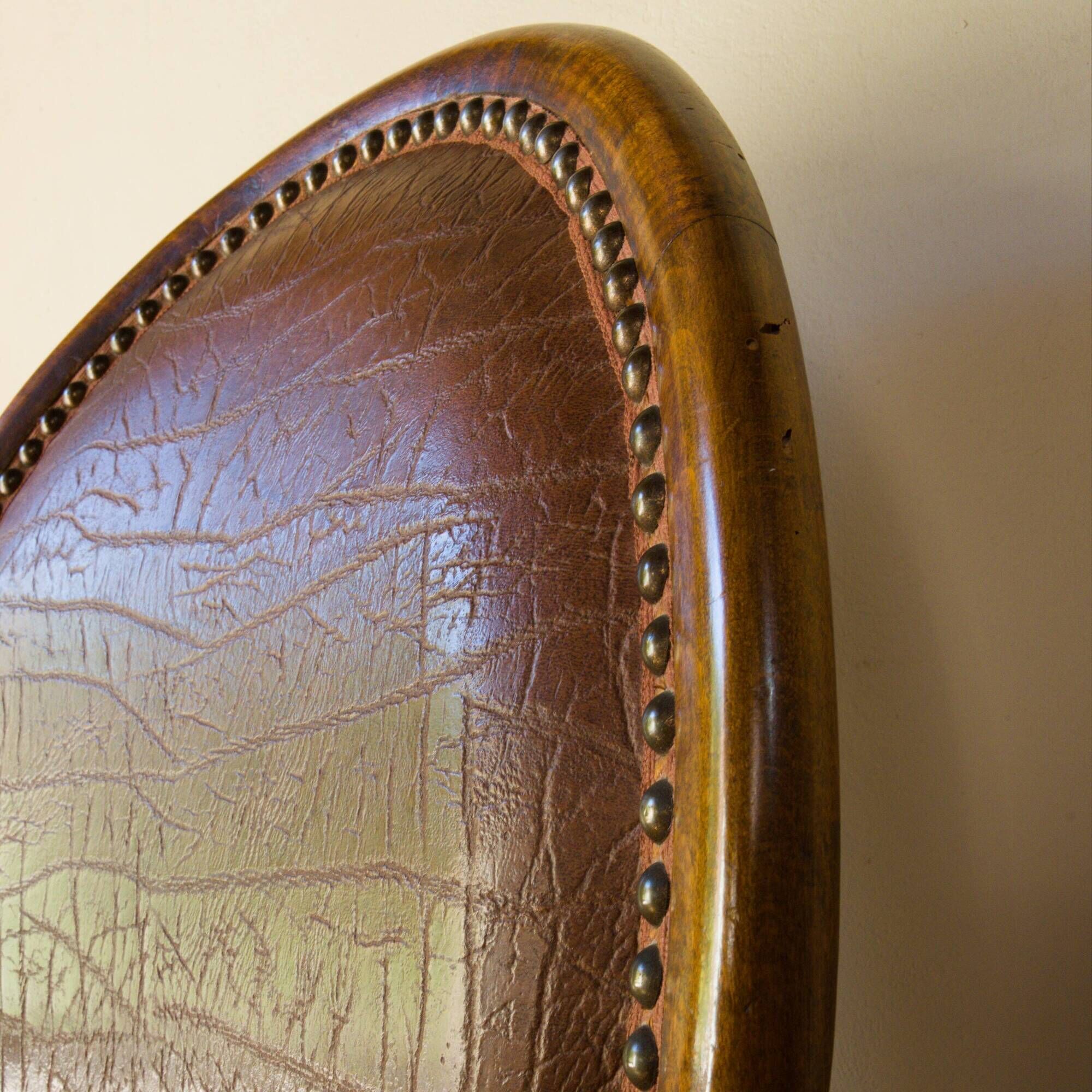 Antique armchair in solid wood and patinated brown leather, early 20th century.
