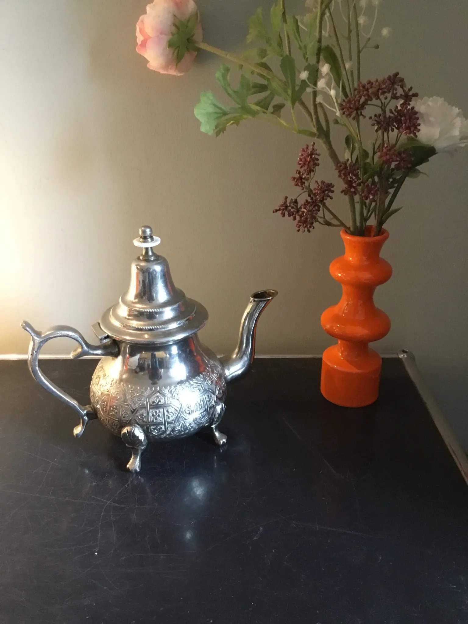 Traditional metal teapot with silver plating, Eastern style, on a stand.