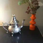 Traditional metal teapot with silver plating, Eastern style, on a stand.