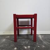 Red wooden stool with woven rush seat.