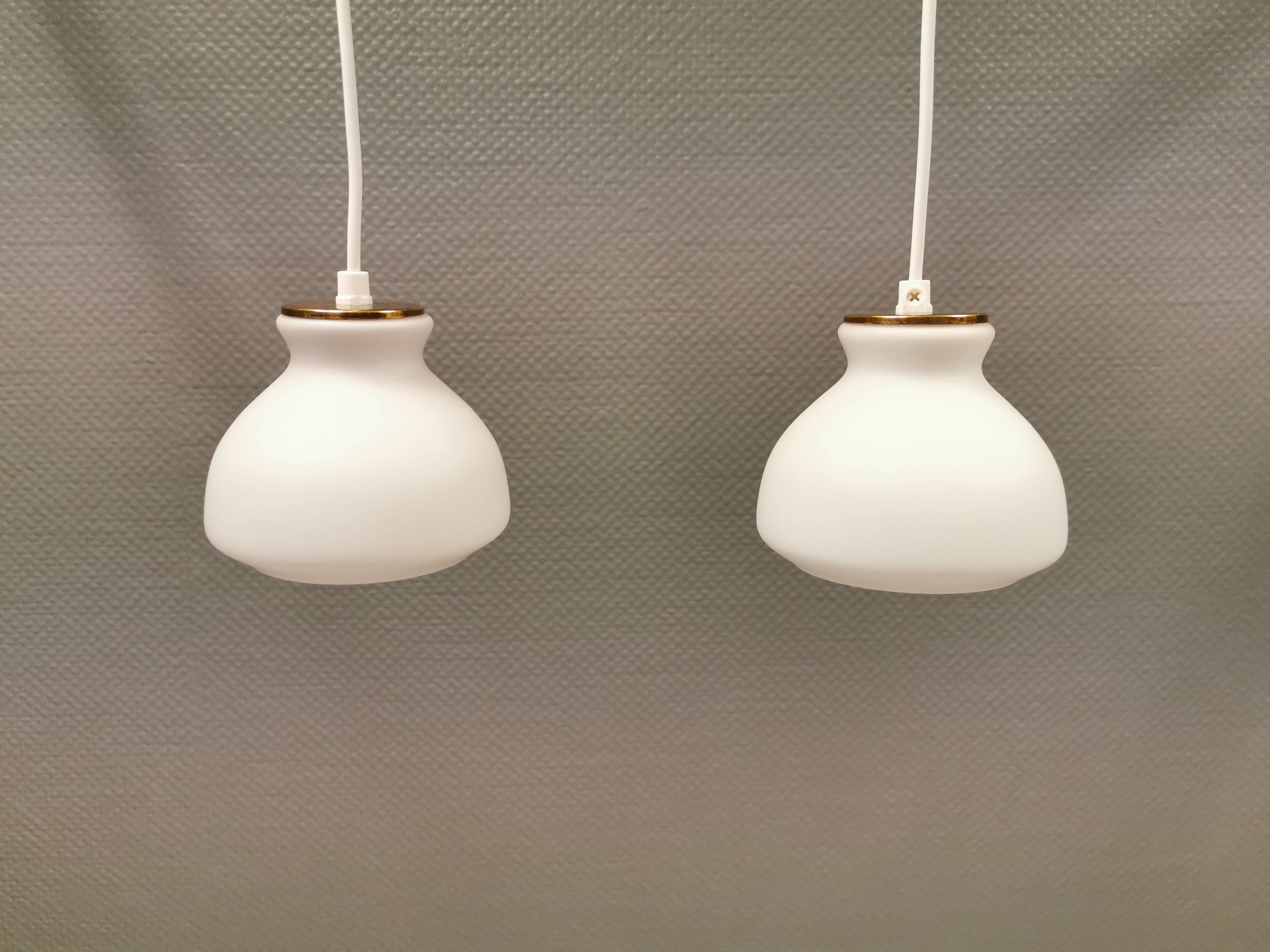 Une paire de lampes suspendues de la verrerie danoise Holmegaard avec abat-jour en verre blanc laiteux.