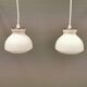 Une paire de lampes suspendues de la verrerie danoise Holmegaard avec abat-jour en verre blanc laiteux.