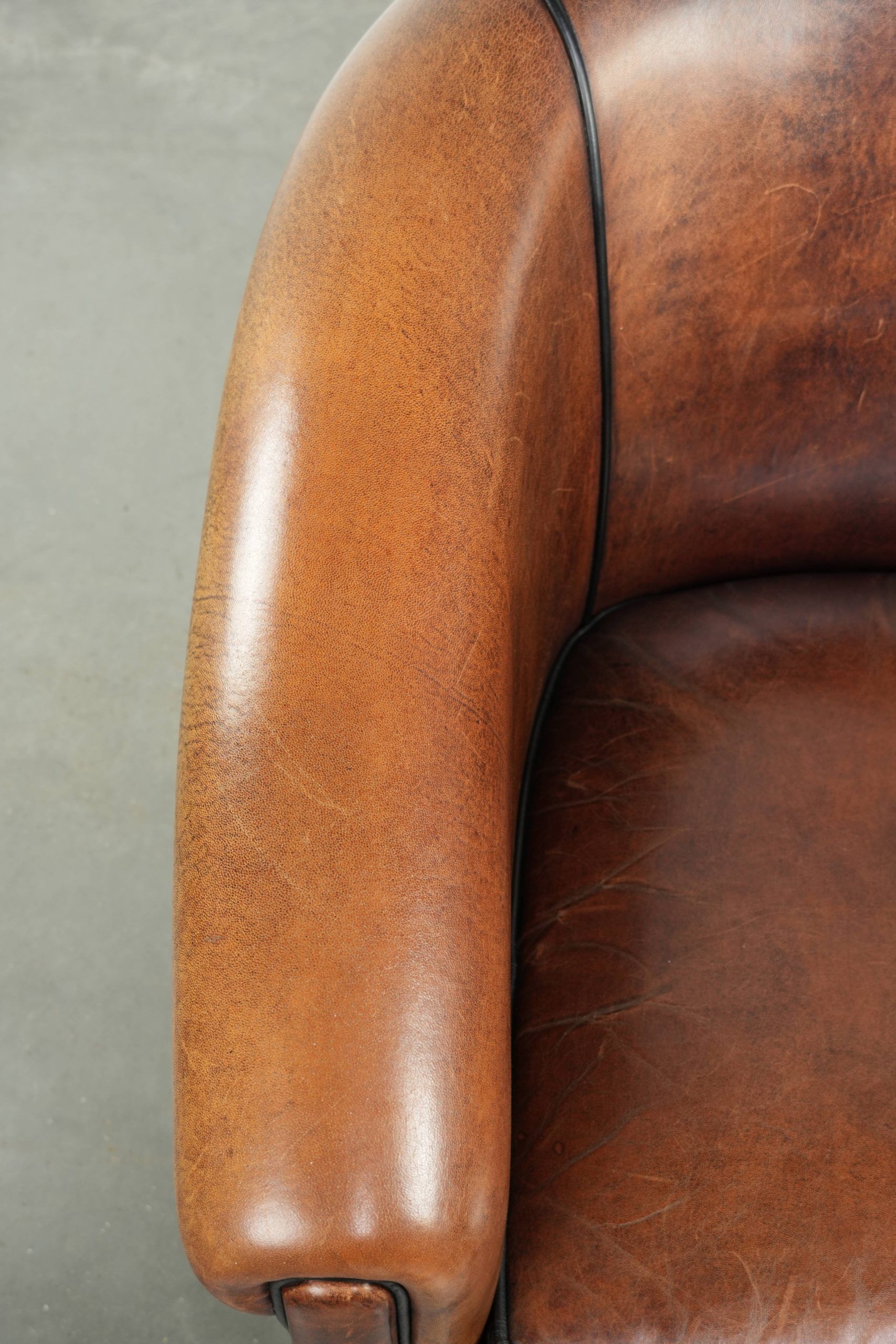 Sheepskin club armchair with deep warm colours and black piping
