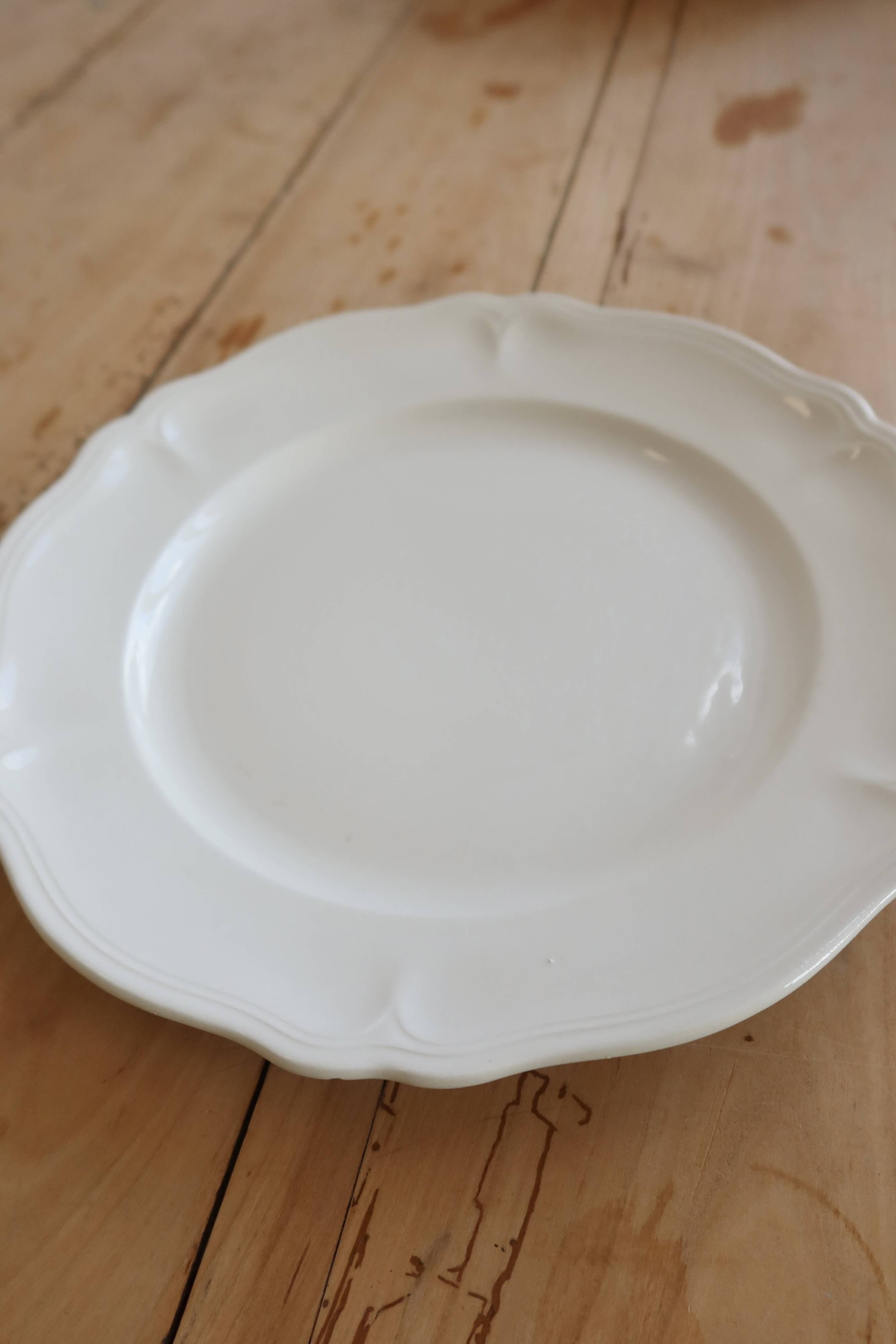 Round vintage ivory earthenware serving dish with scalloped rim.