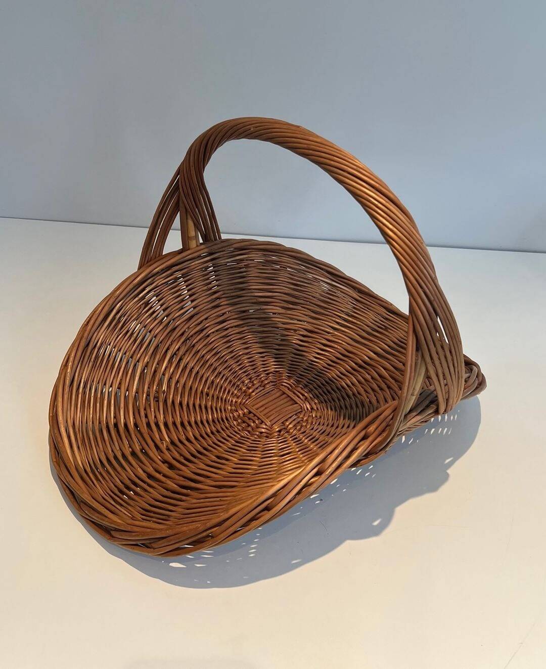 Woven Rattan Log Holder in a Semi-Round Shape with a Central Arched Handle.