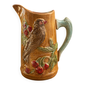 Old earthenware jug with bird and cherry decoration.