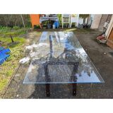 Vintage table with a glass top and smoked plastic trestle legs.