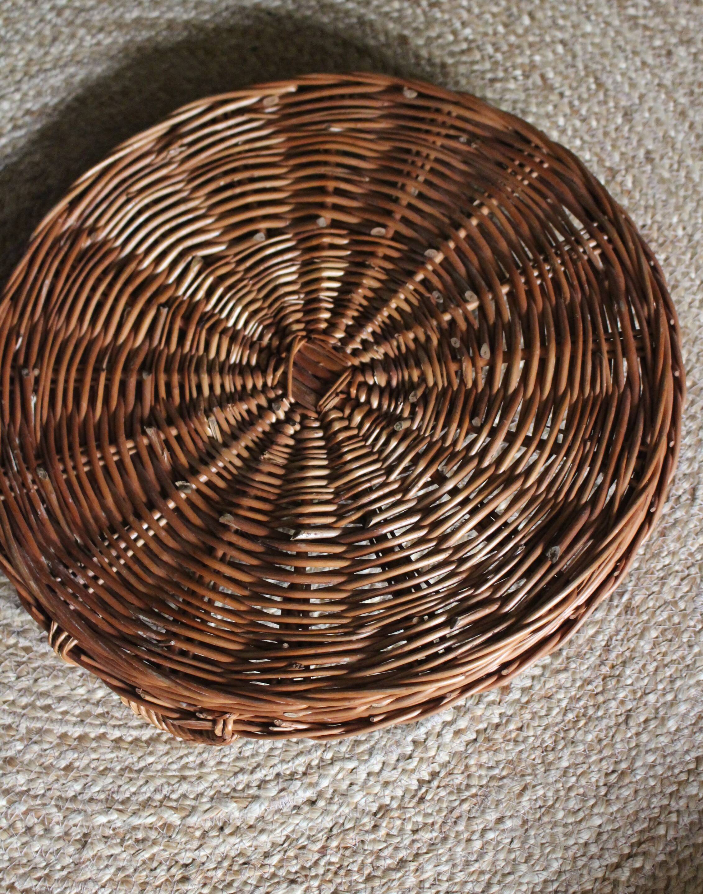 Large round dark wicker tray with two handles.