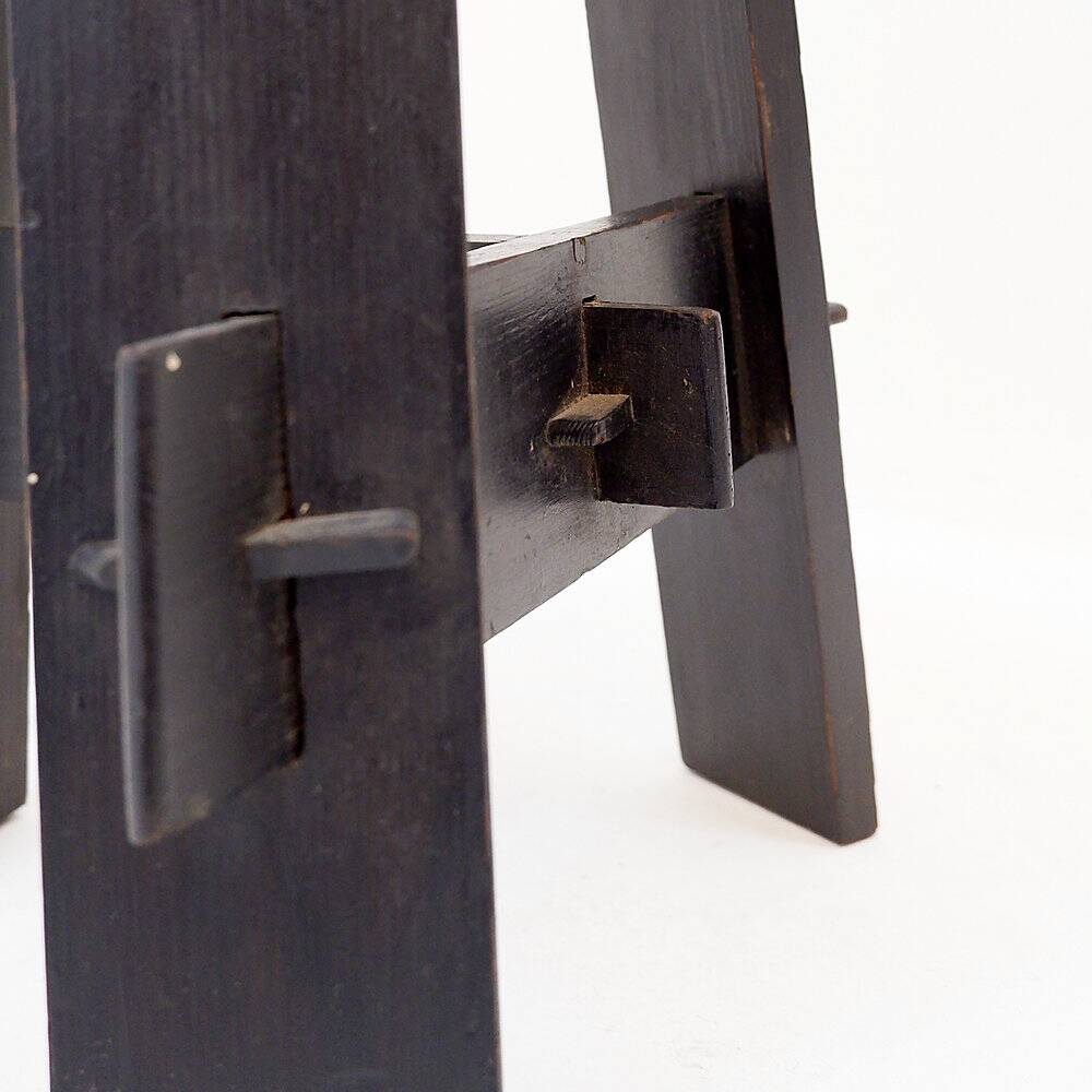 Vintage black-stained wooden tripod stool with mortise joints.