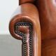 Large sheepskin wingback chair with black piping and decorative nails