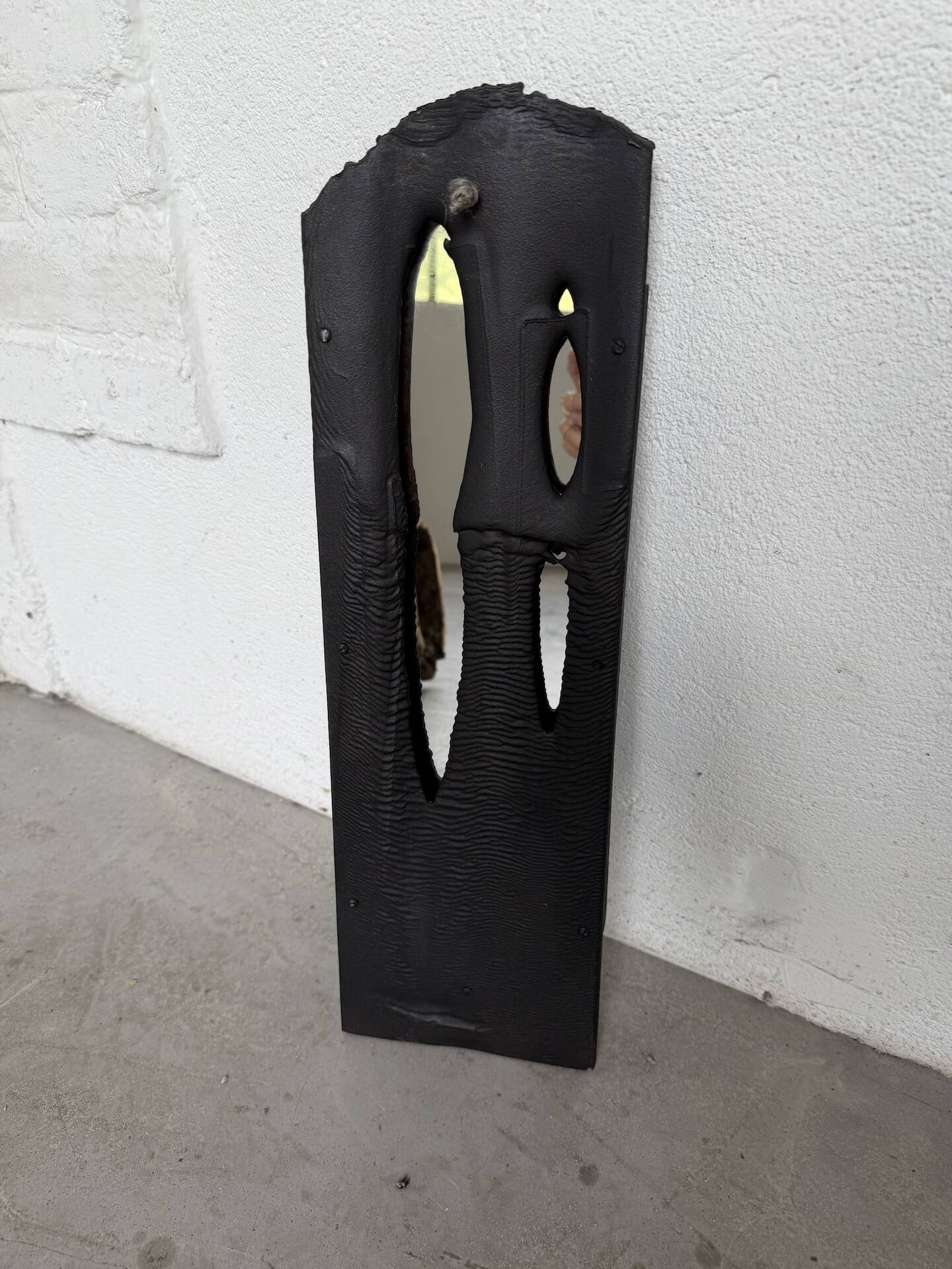 Brutalist hammered mirror, free-form, patinated metal.