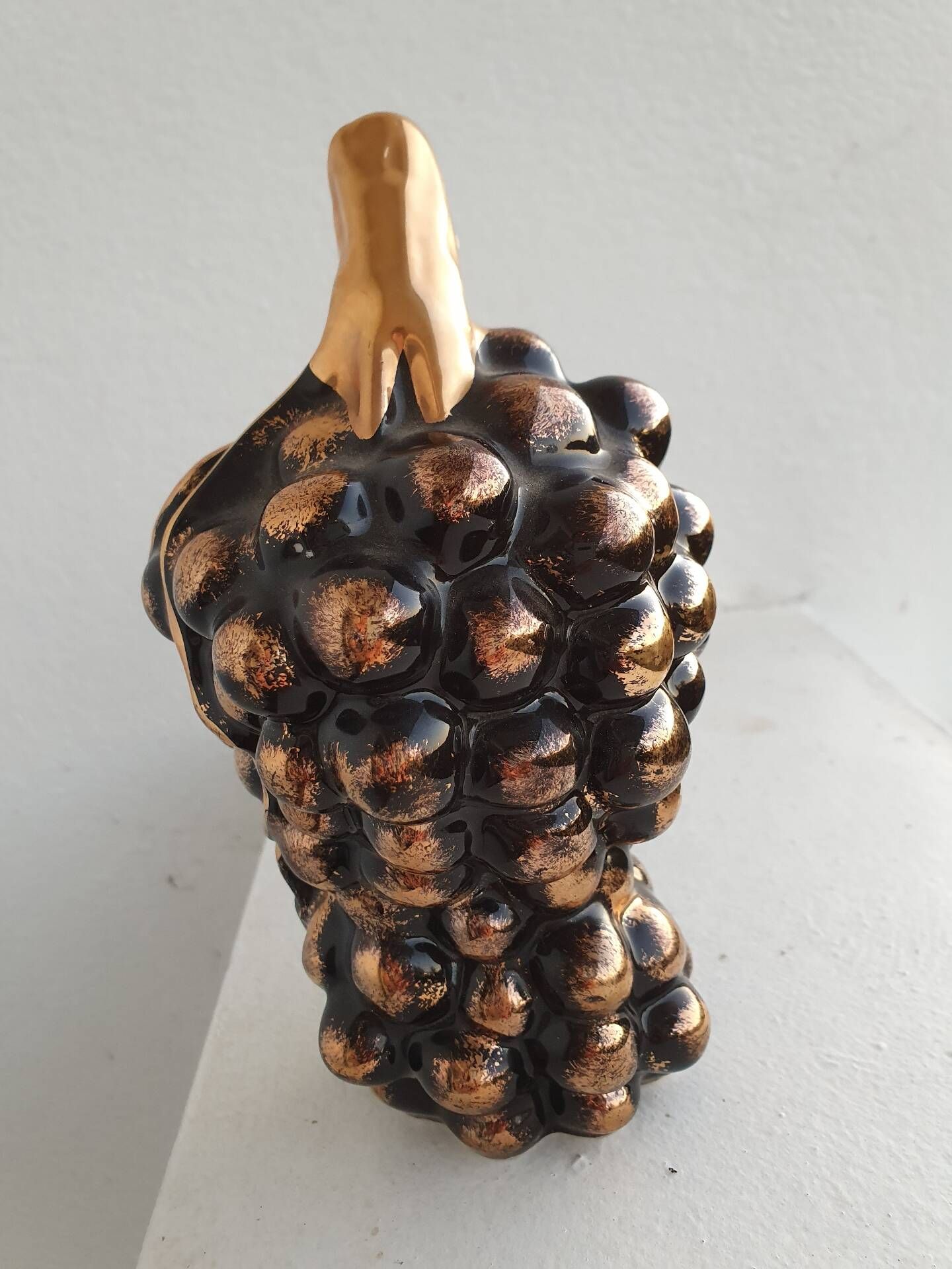 Beautiful black and gold ceramic bottle in the shape of a bunch of grapes.