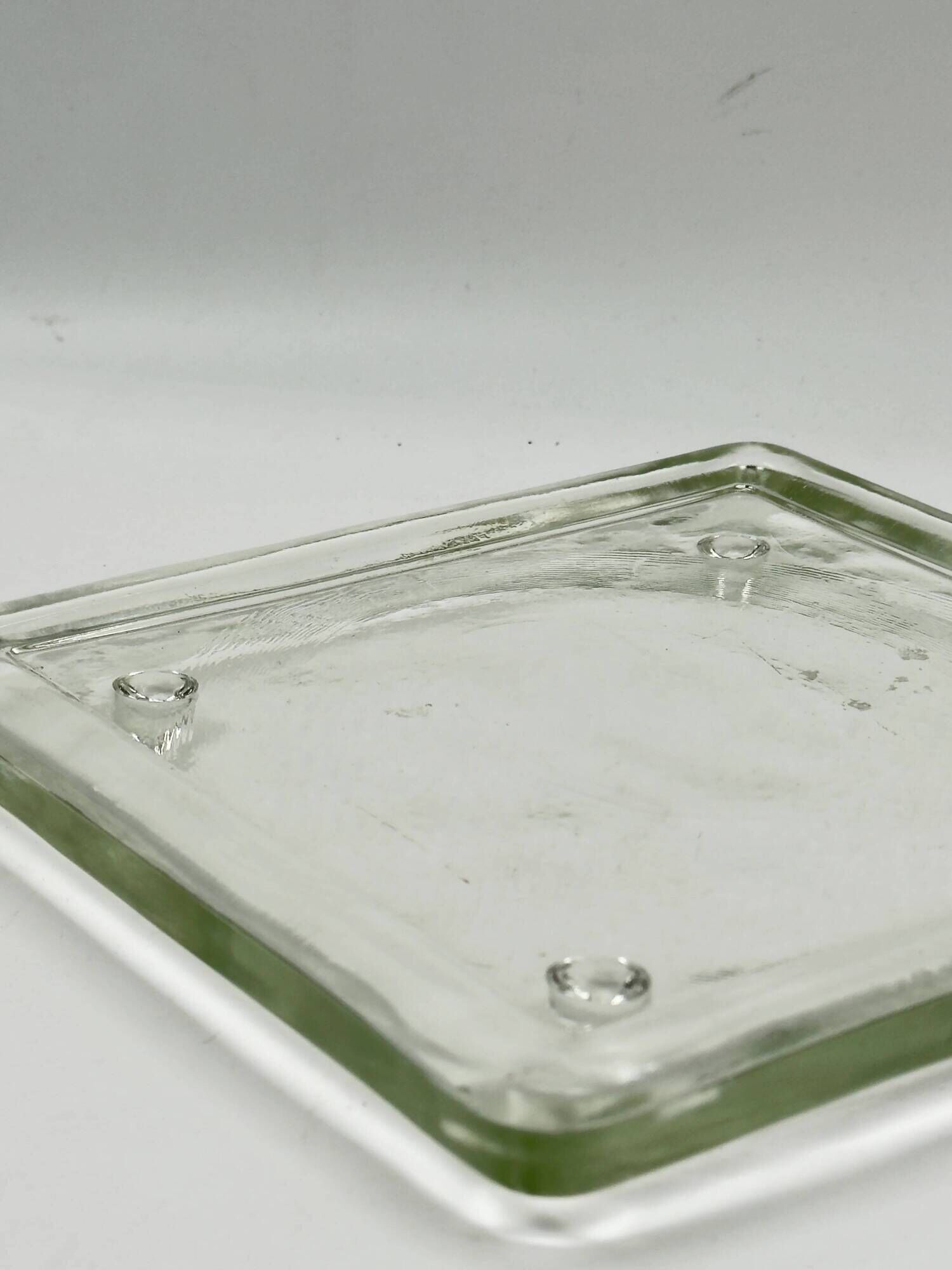 Vintage square serving tray in pale green tinted transparent glass with raised feet.