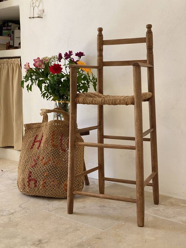 Ancienne chaise haute d’enfant en bois massif avec assise paillée.