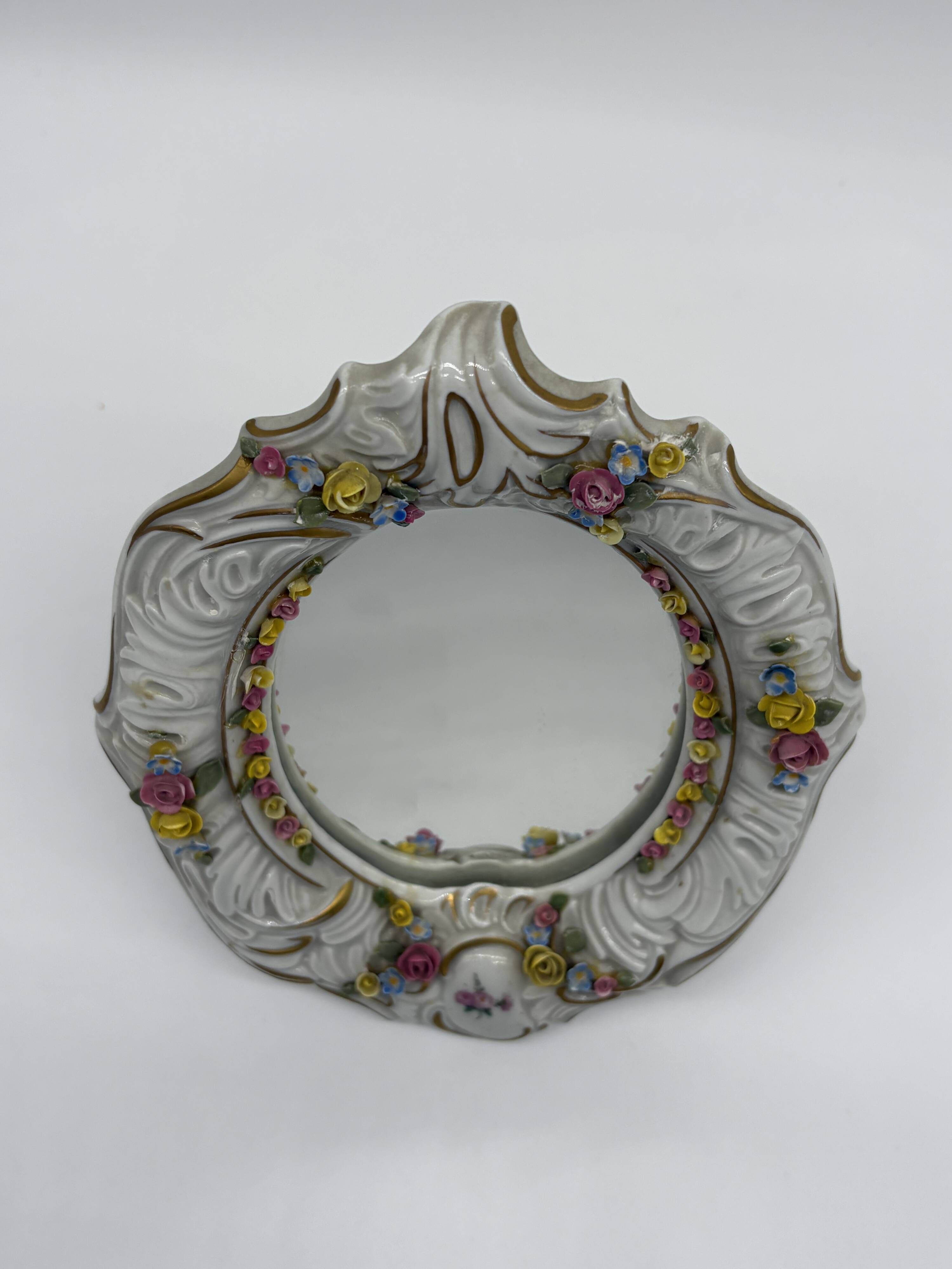 Antique porcelain mirror from Dresden with relief flowers and rococo decoration.