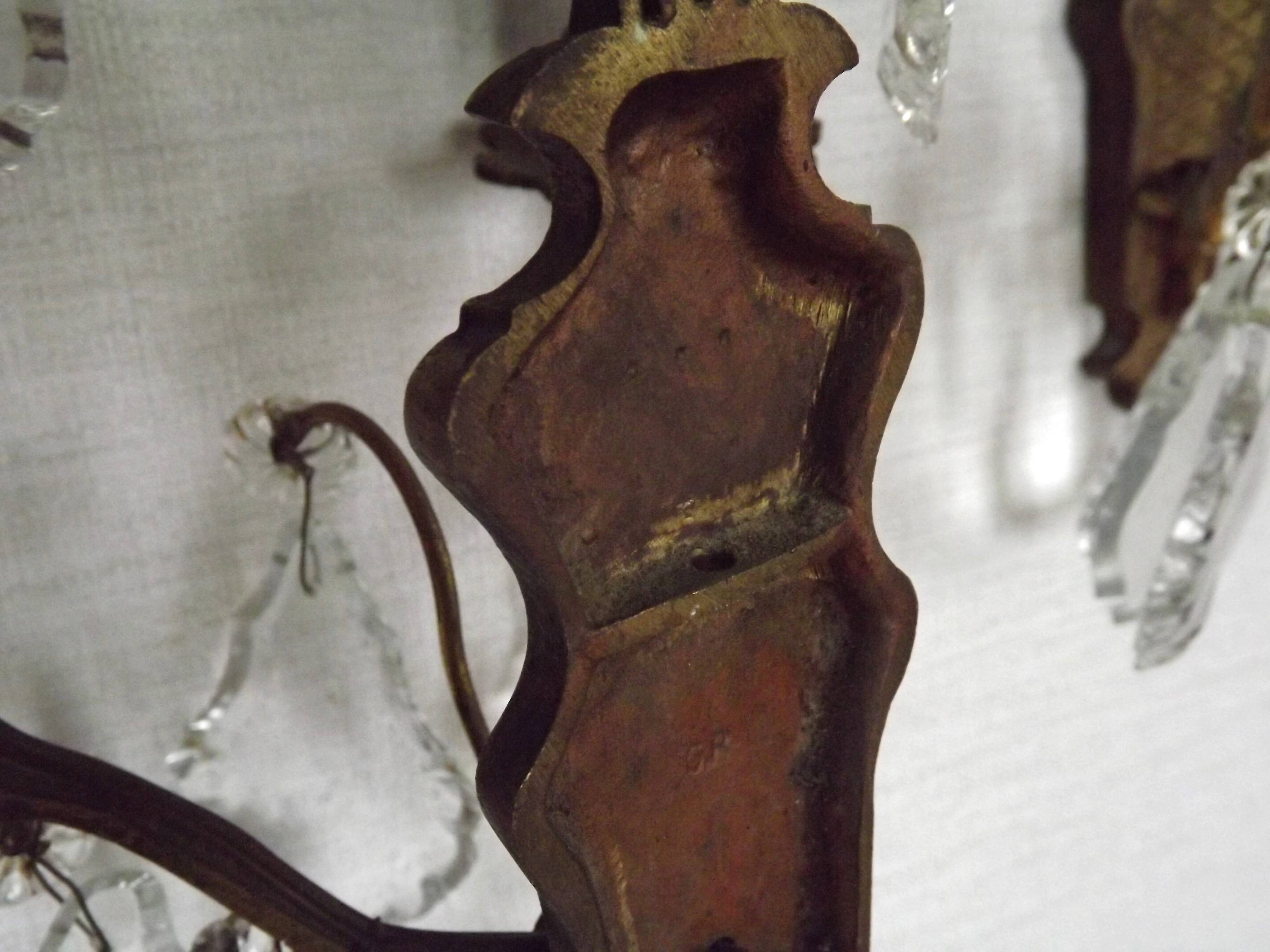 Pair of French antique brass double wall lights with assorted crystals.