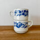 Set of 2 antique earthenware cups with blue floral pattern.