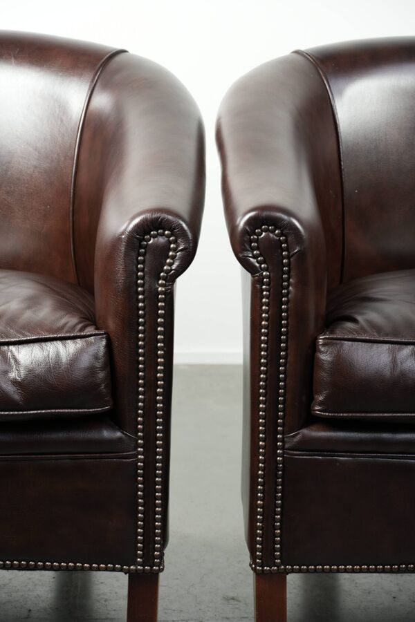 Ensemble de deux fauteuils club en cuir de vache en bon état avec un design anglais.