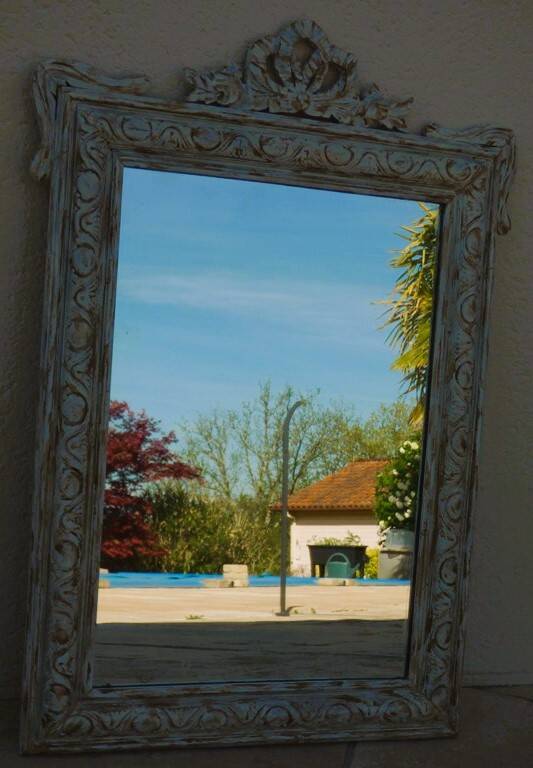 Chic and stylish old mirror with carved wooden frame in limed white and gold