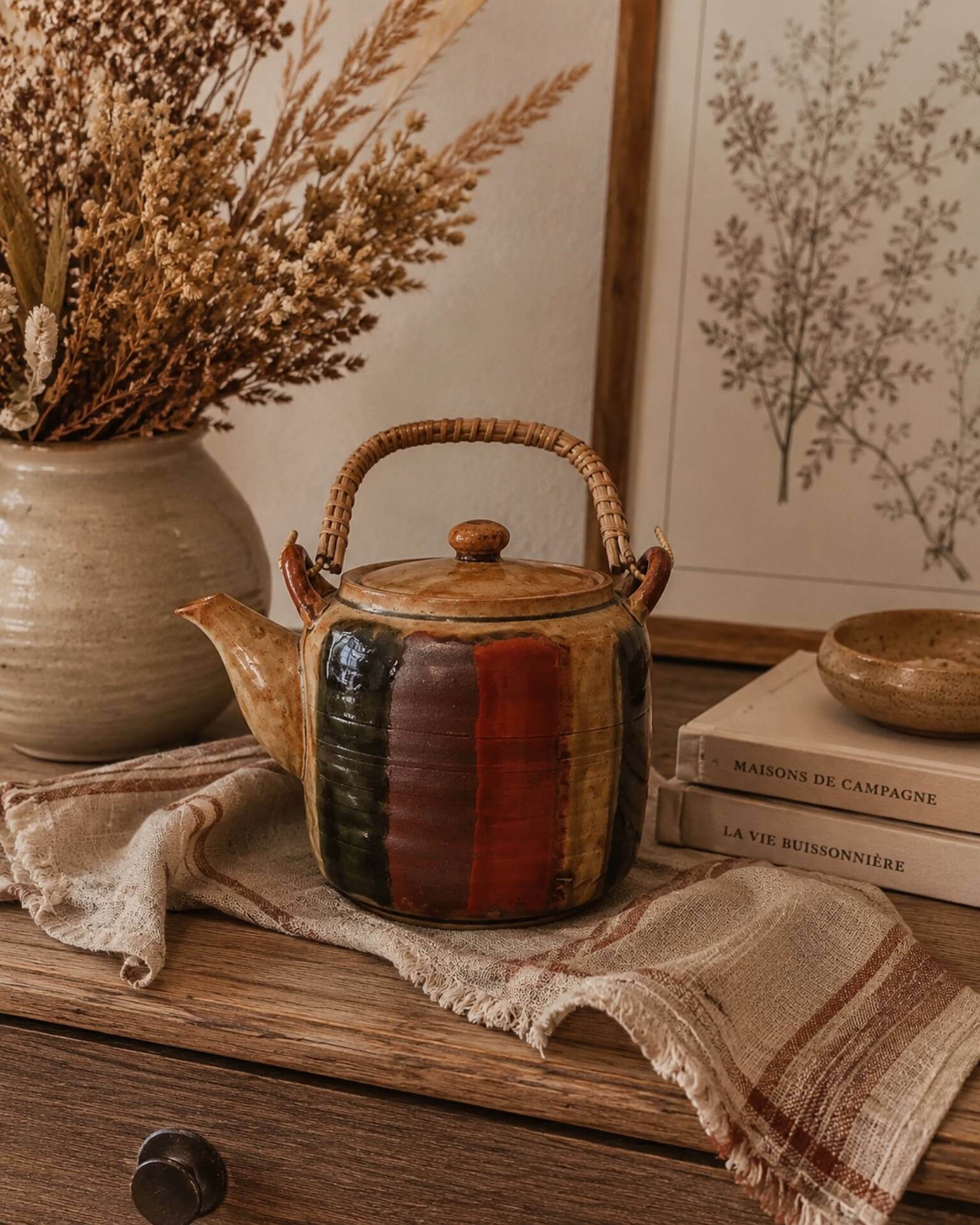 Vintage ceramic teapot with an enamel finish, rattan handle, warm tones.