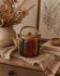 Vintage ceramic teapot with an enamel finish, rattan handle, warm tones.