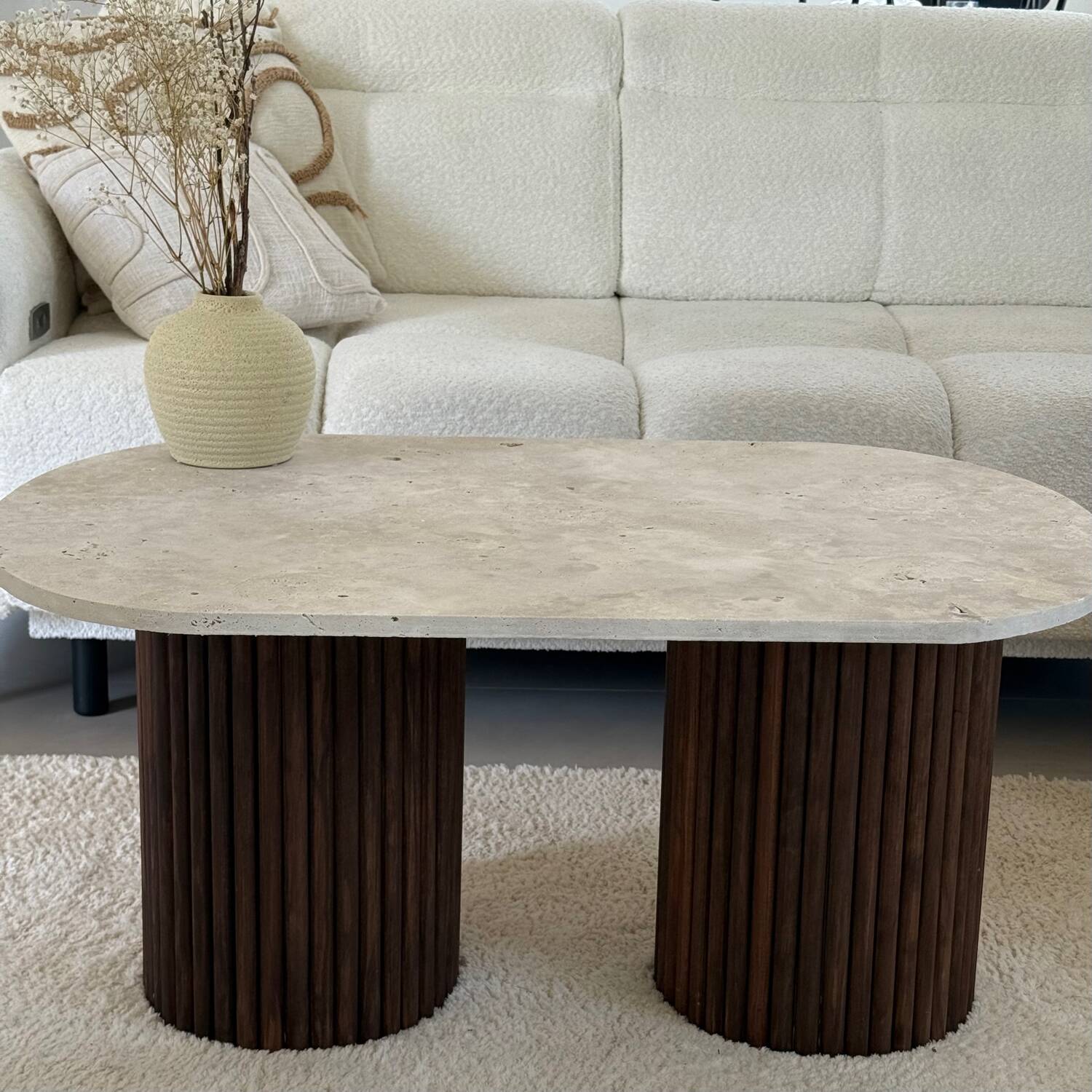 Oval coffee table in travertine and fluted wood.