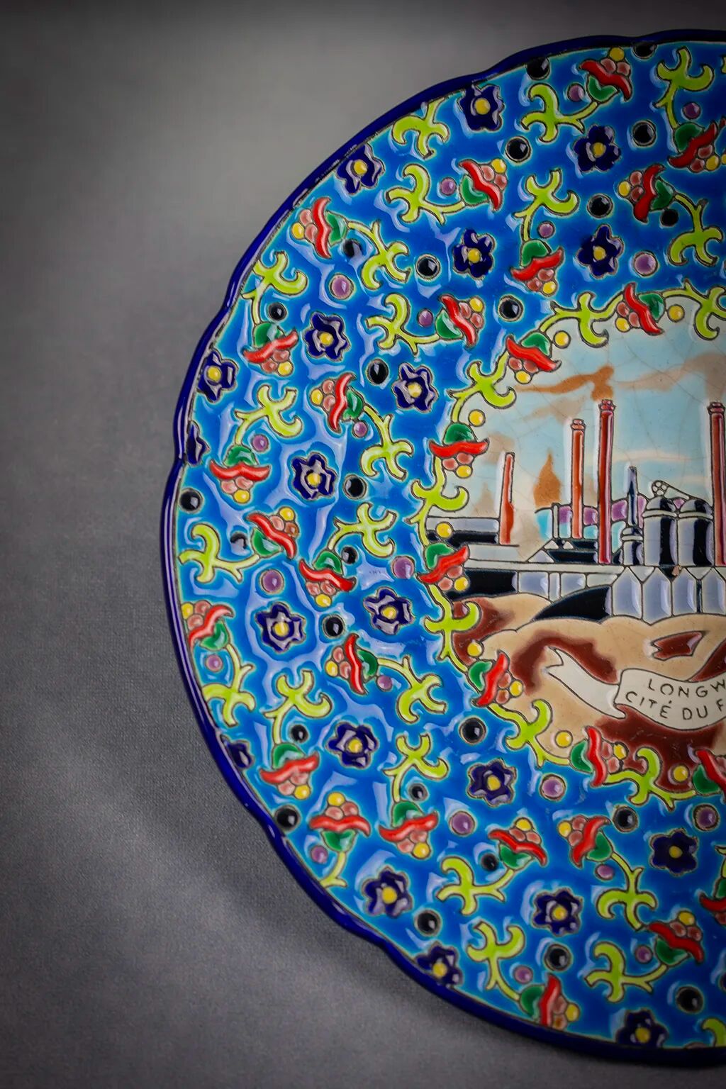 Longwy plate with polychrome enamels, decorated with the "City of Iron" motif.