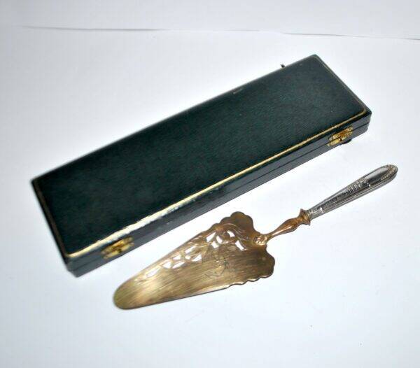 Antique silver-plated pie server with a brass blade decorated with roses.