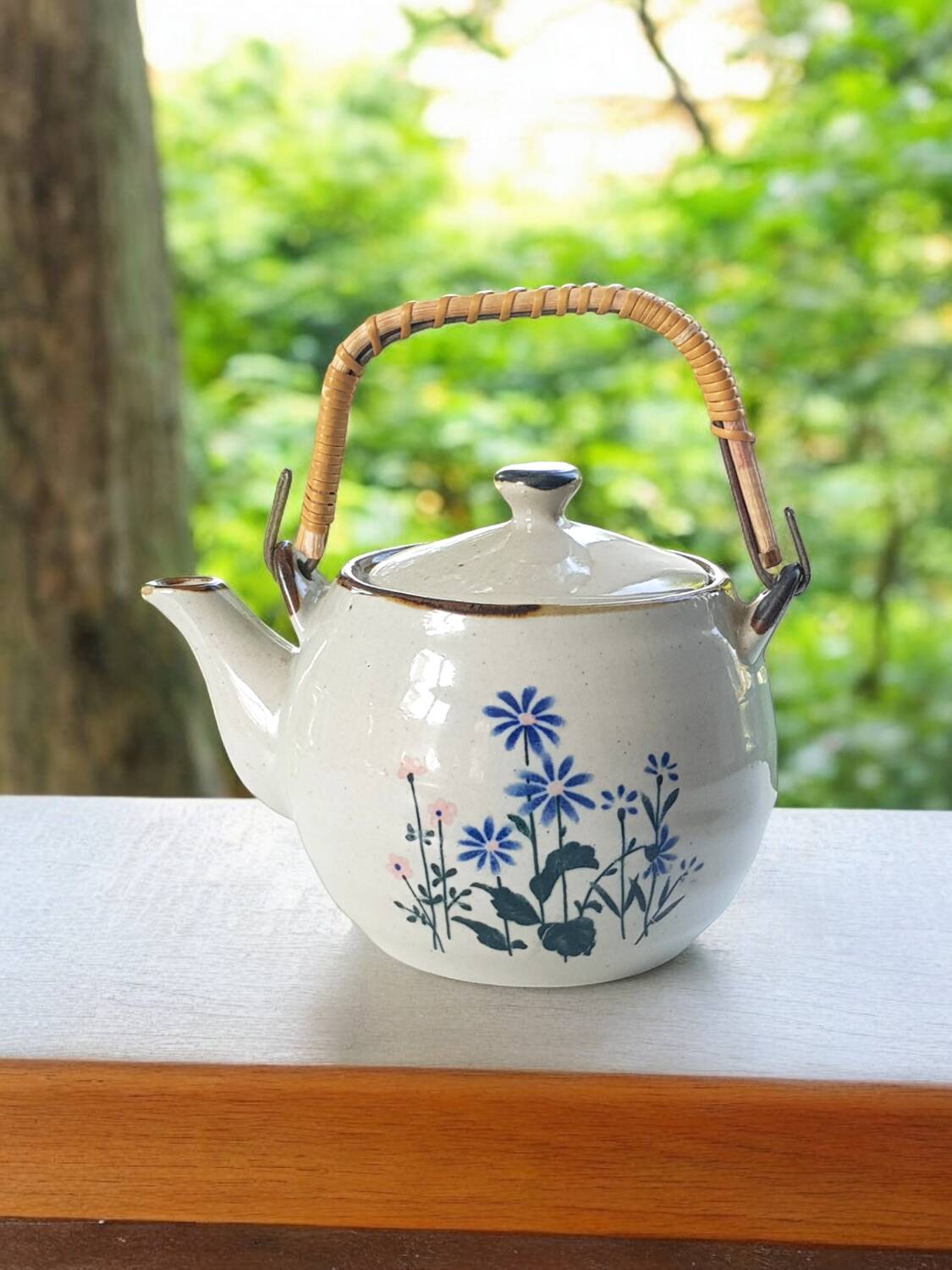 Théière en grès fleurie et anse en rotin.
