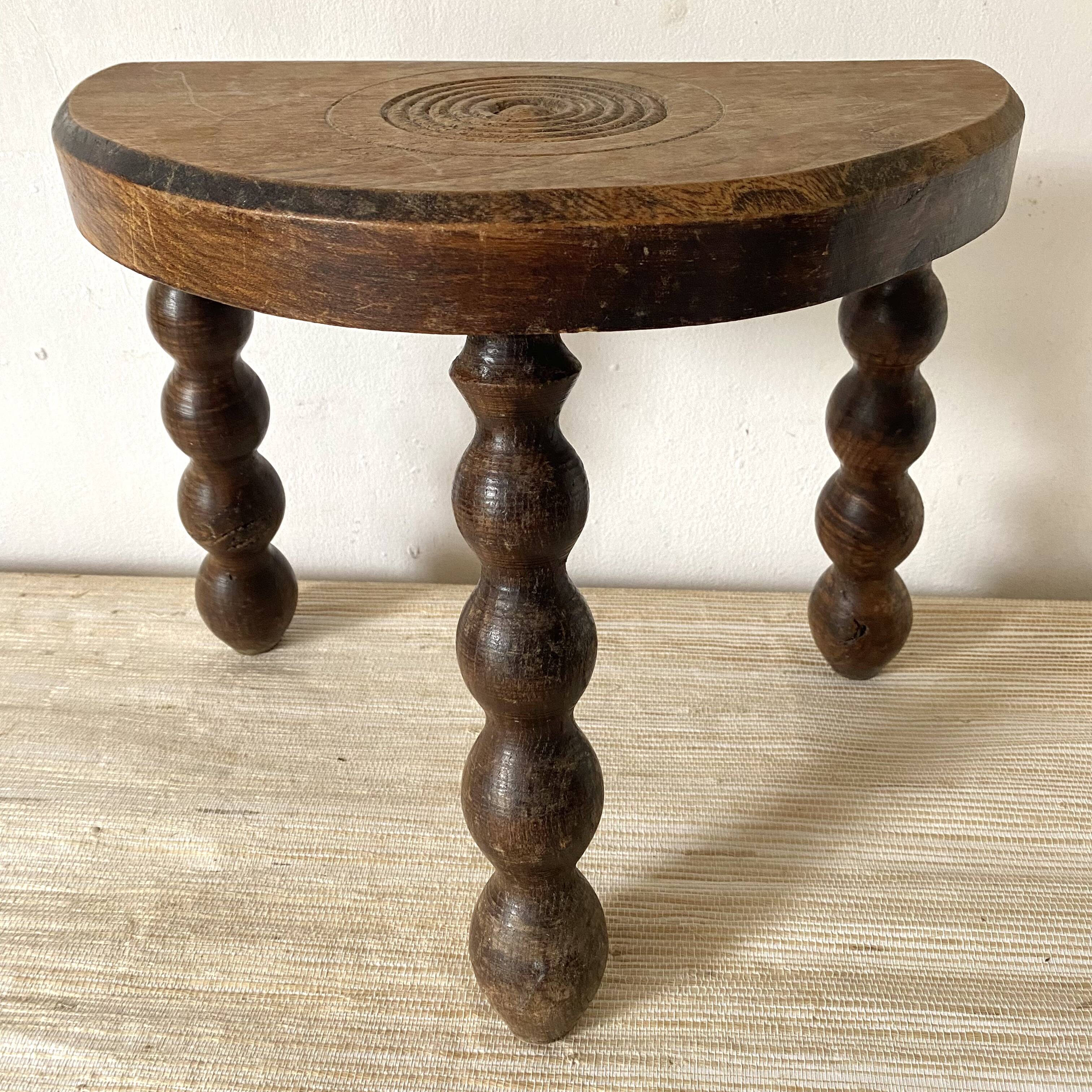 Tabouret tripode en bois sculpté, assise demi lune