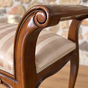 Two-seater bench in carved wood, with curved armrests.