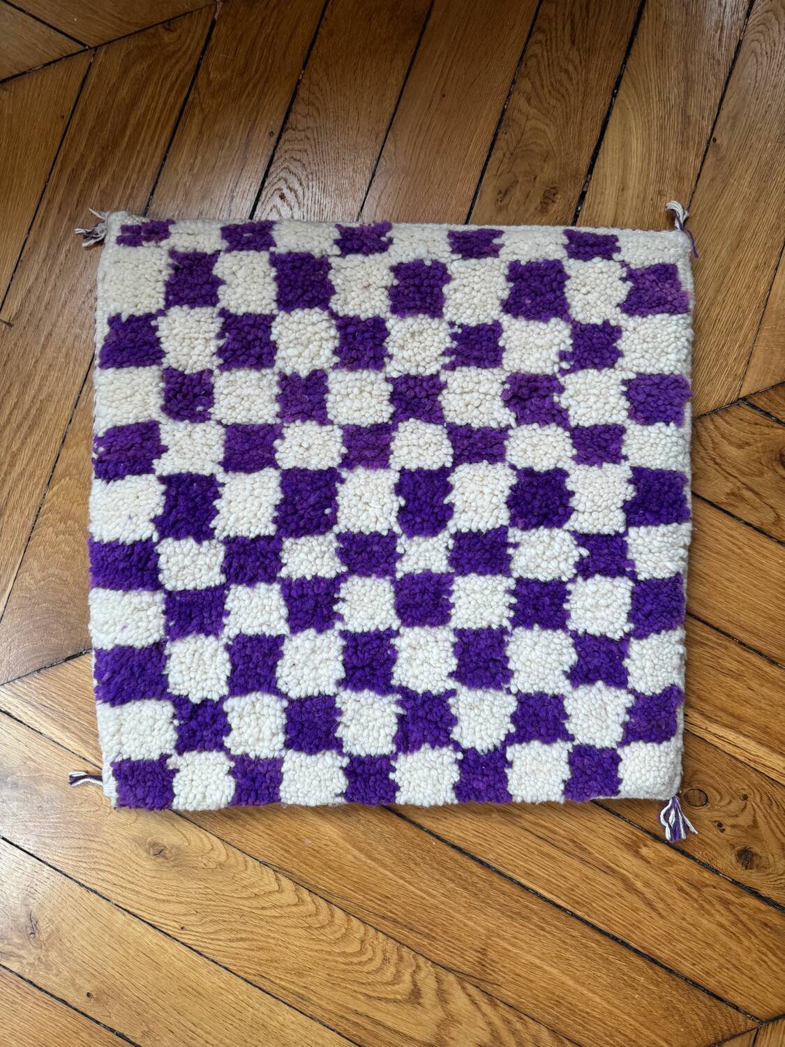 Square cushion cover with a checkered pattern.