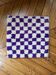 Square cushion cover with a checkered pattern.