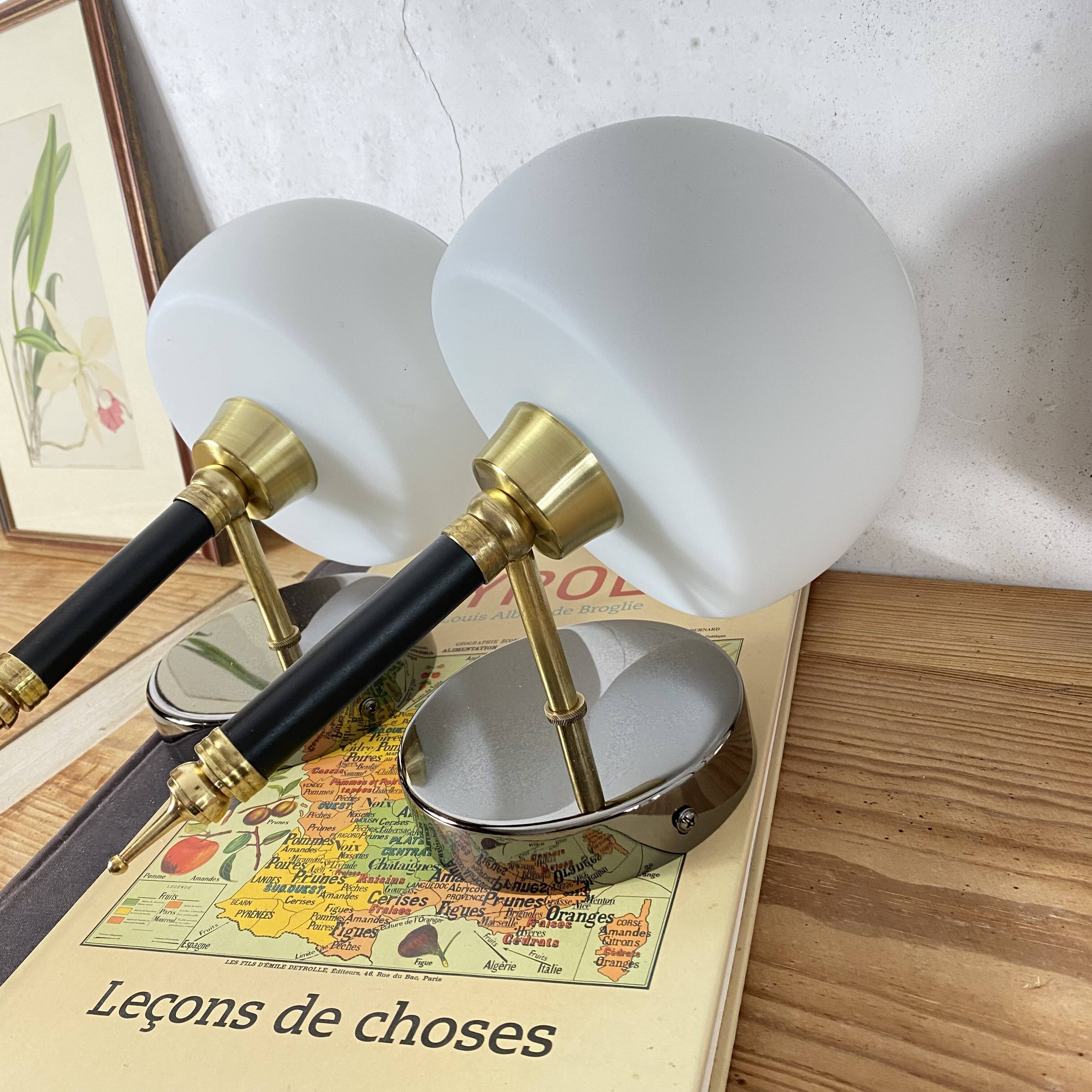 Pair of wall sconces with brass torch and white glass globe.