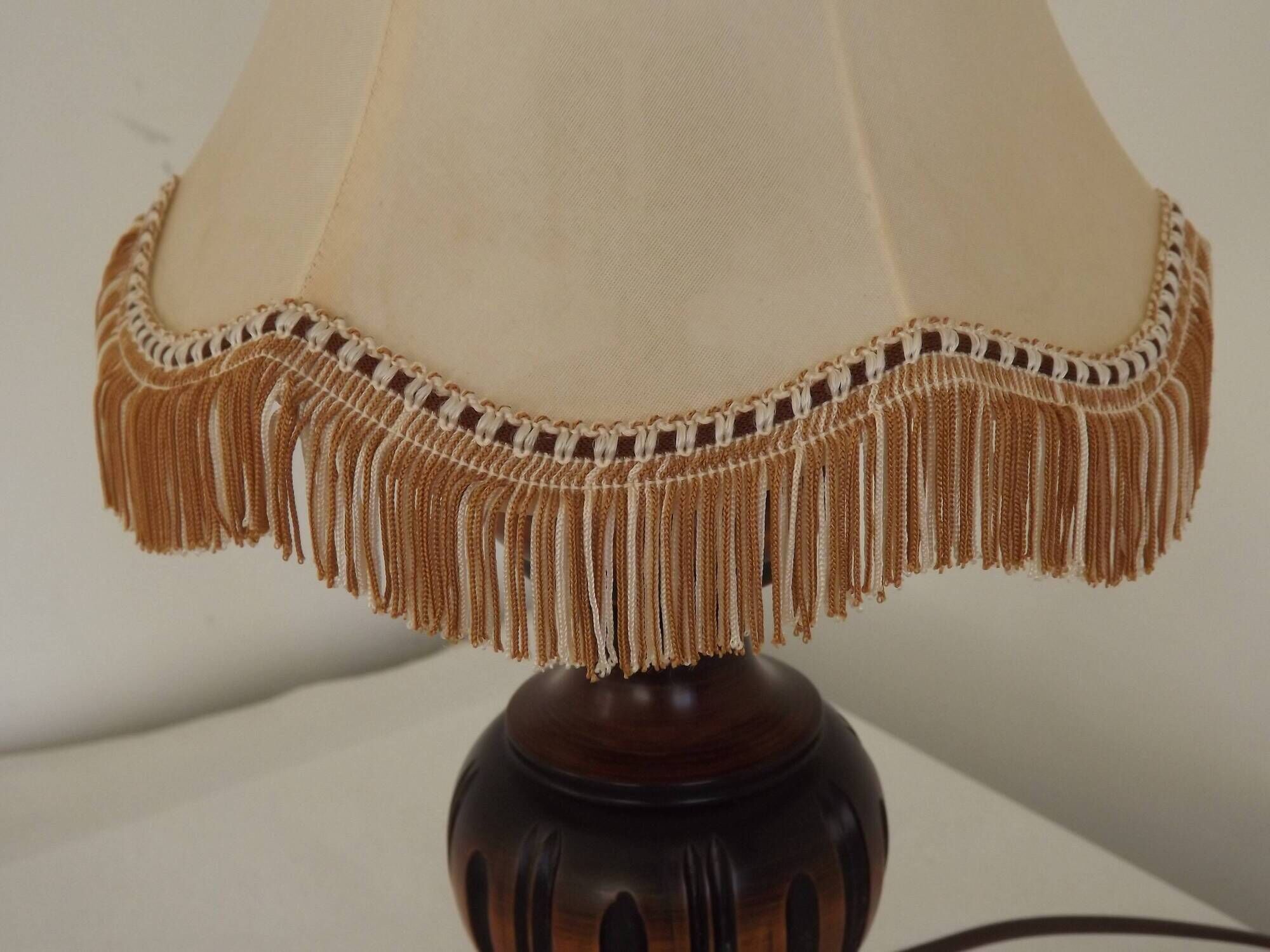 Mid-century French table lamp made of turned carved wood with a fringed shade.