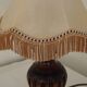 Mid-century French table lamp made of turned carved wood with a fringed shade.