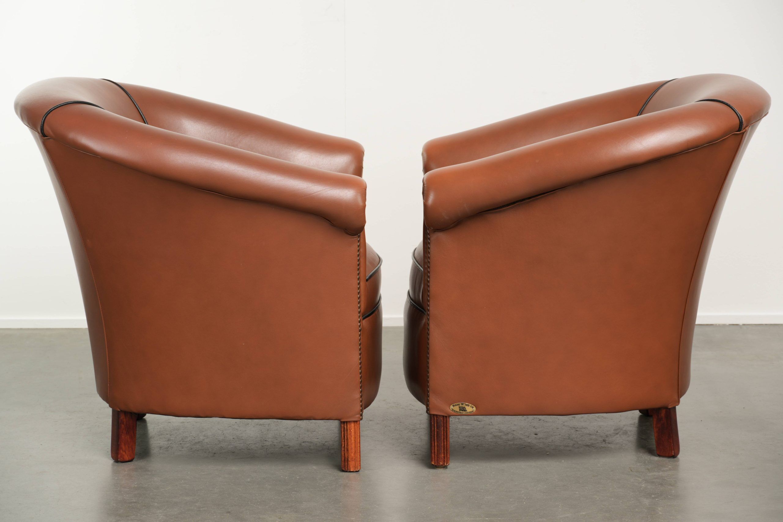 Ensemble de 2 fauteuils club en cuir de vache en bon état dans le style anglais.