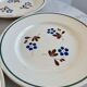 Set of 4 small flat plates with floral designs.